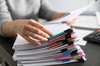 picture of a person with their hand over a stack of partitioned sheets of paper