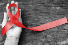 Red AIDS awareness ribbon held in an open palm