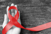 Red AIDS awareness ribbon in an open palm