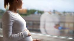 image of a pregnant woman looking out a window