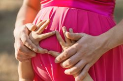 photo of a pregnant woman's belly with a child's hands on it