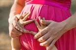 photo of a child's hands on a pregnant woman's belly