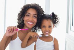 photo of a woman and her daughter brushing their teeth