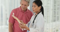 a doctor showing a model of a spine to a patient