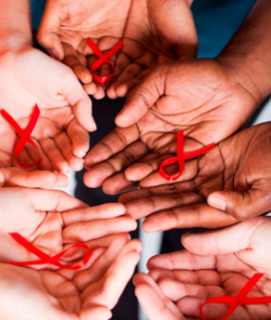 photo of several hands holding red ribbons