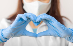 photo of a health care worker making a heart symbol with her hands