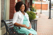 photo of a woman who is pregnant sitting outside on a bench
