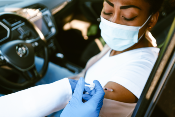 woman getting vaccine through car window