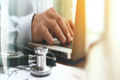 close up physician on laptop with stethoscope on desk