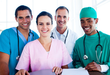 A multicultural group of four healthcare providers, in scrubs, standing together