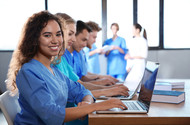 Female nursing student in class at her computer smiling.