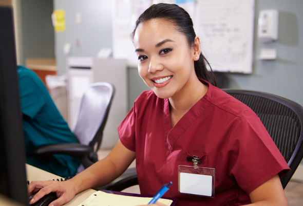 A nurse wearing red scrubs sitting at desk