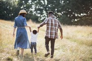 a man and woman walking with their child in a field