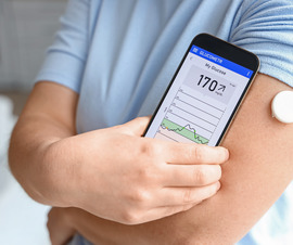 Man checking his blood sugar using his phone and a wearable device