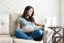 Pregnant woman on a computer accessing virtual assistance