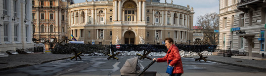 old woman pushing baby pram in front of barricades