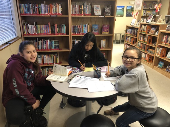 Students from the Nooksack Indian Tribe with books at a table participating in after-school tutoring programs at the library