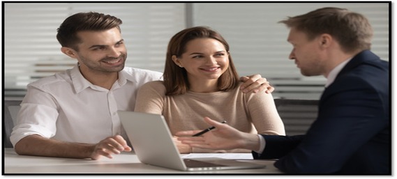 Man and woman couple getting assistance from a man on his laptop in an office