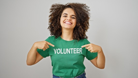 Woman pointing to volunteer uniform smiling over isolated white background