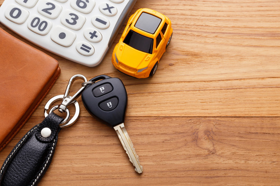 Car key with calculator and pocket money on wood table background