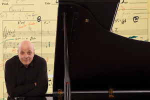 Composer Charles Fox leans on a grand piano in front of his sheet music