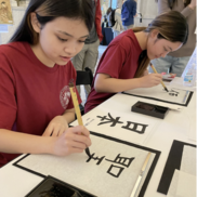 Japanese Culture Day—Two young girls practice Japanese calligraphy.