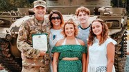 Soldier posing with family and award