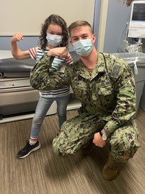 DVIDS Photo of service member and child in masks and flexing their arm.