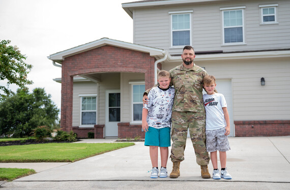An Air Force tech sergeant and his kids stand outside of base housing