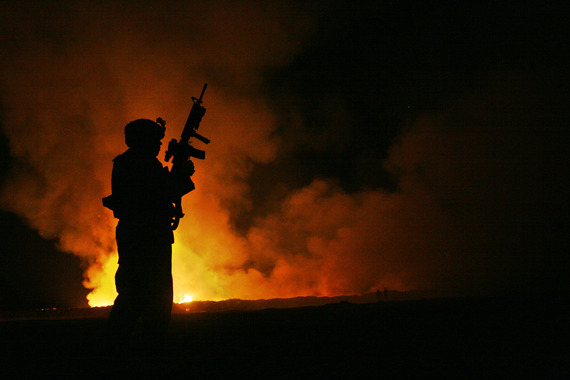 Service member stands in front of a burn pit