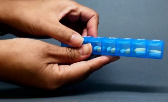Woman's hands open a pill organizer