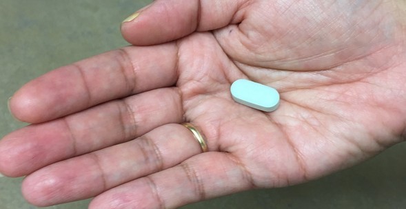 Woman's hand with a pill in her palm