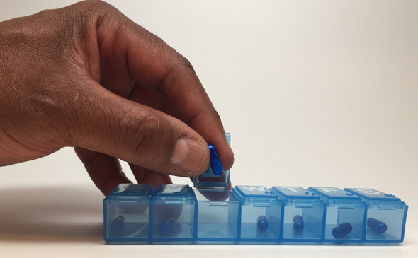 Man's hand with a daily pill box