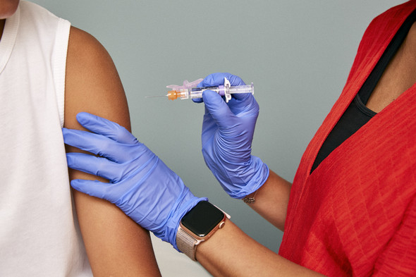 Healthcare provider about to inject a vaccine into an adult's arm.