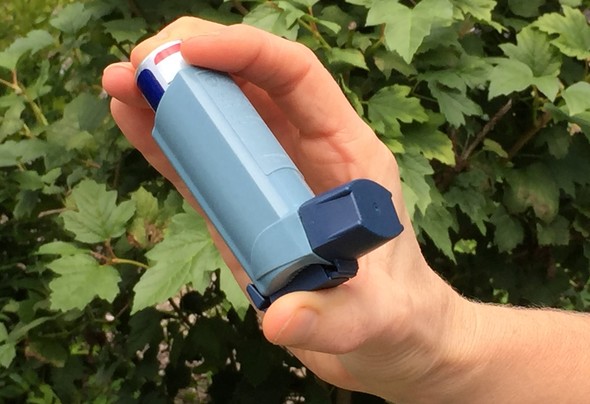 Person's hand holding an asthma inhaler