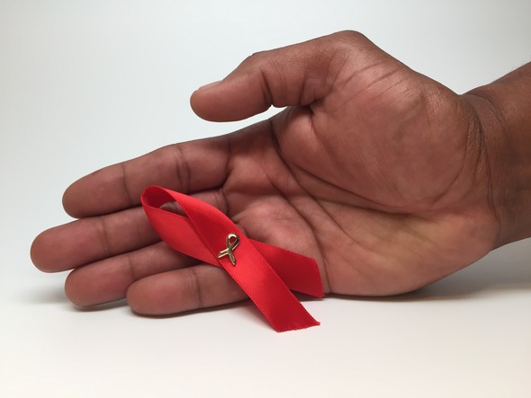 Photo of red HIV awareness ribbon in a person's hand