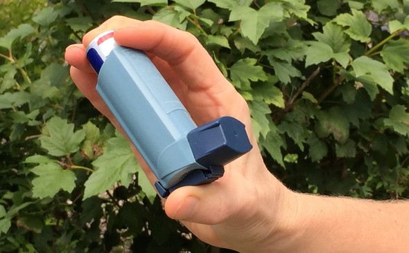 Person's hand holding an asthma inhaler