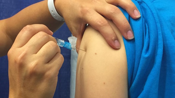 hand injects syringe needle into shoulder 