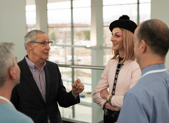 Four people facing each other and having a conversation. Two people are facing away from the camera.