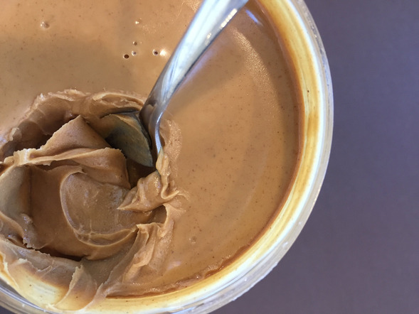 Peanut butter with a spoon stuck in it.