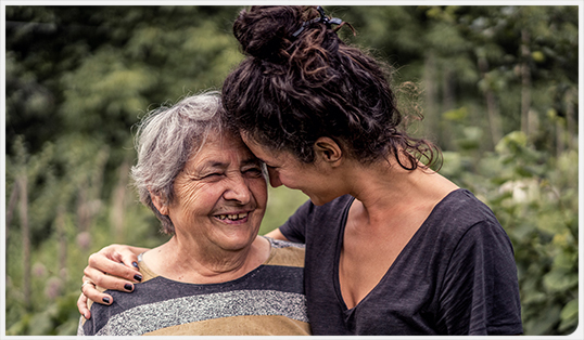 Younger woman smiling with arm around older woman