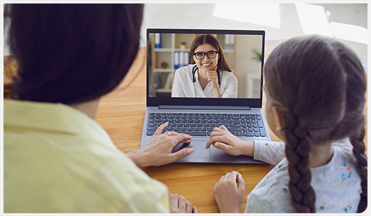 A mother and daughter on a telehealth call with a doctor