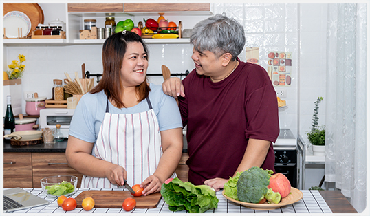 Two people cutting vegetables in a kitchen