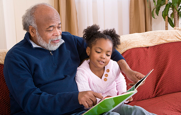 A grandfather reading to his granddaughter.
