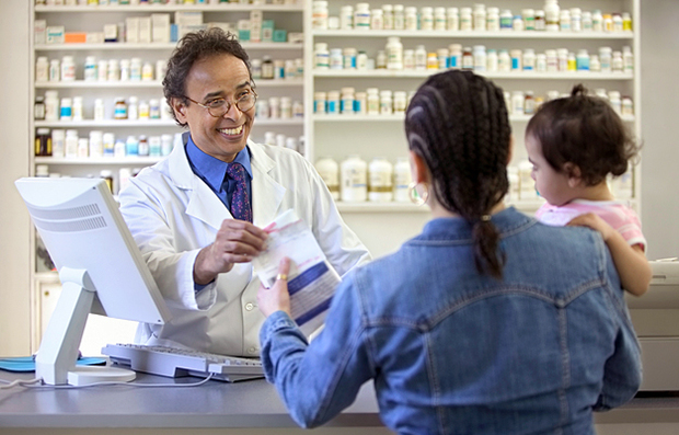 A pharmacist handing a woman her prescription.