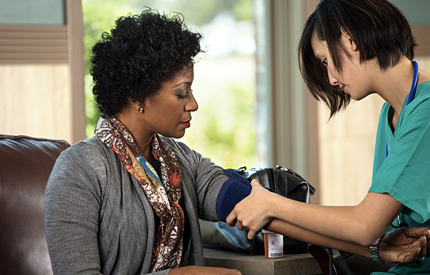 A healthcare worker setting up to take a woman's blood pressure.