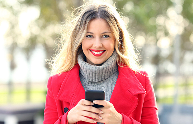 A smiling woman holding a cell phone.