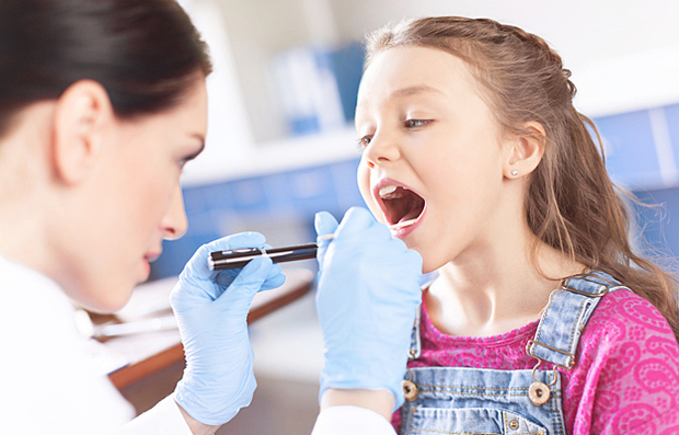 A doctor examining a child's throat with a spatula and flashlight.