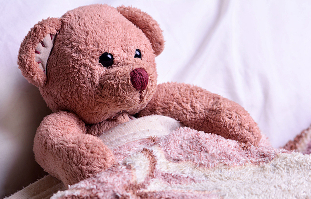 A teddy bear tucked into bed.