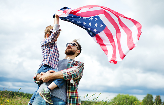 A veteran and his son waving an American flag in the air.